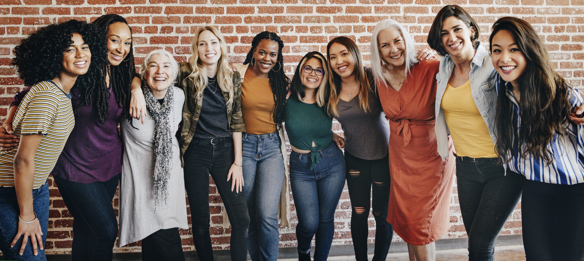 Cheerful diverse women standing in front of a red brick wall